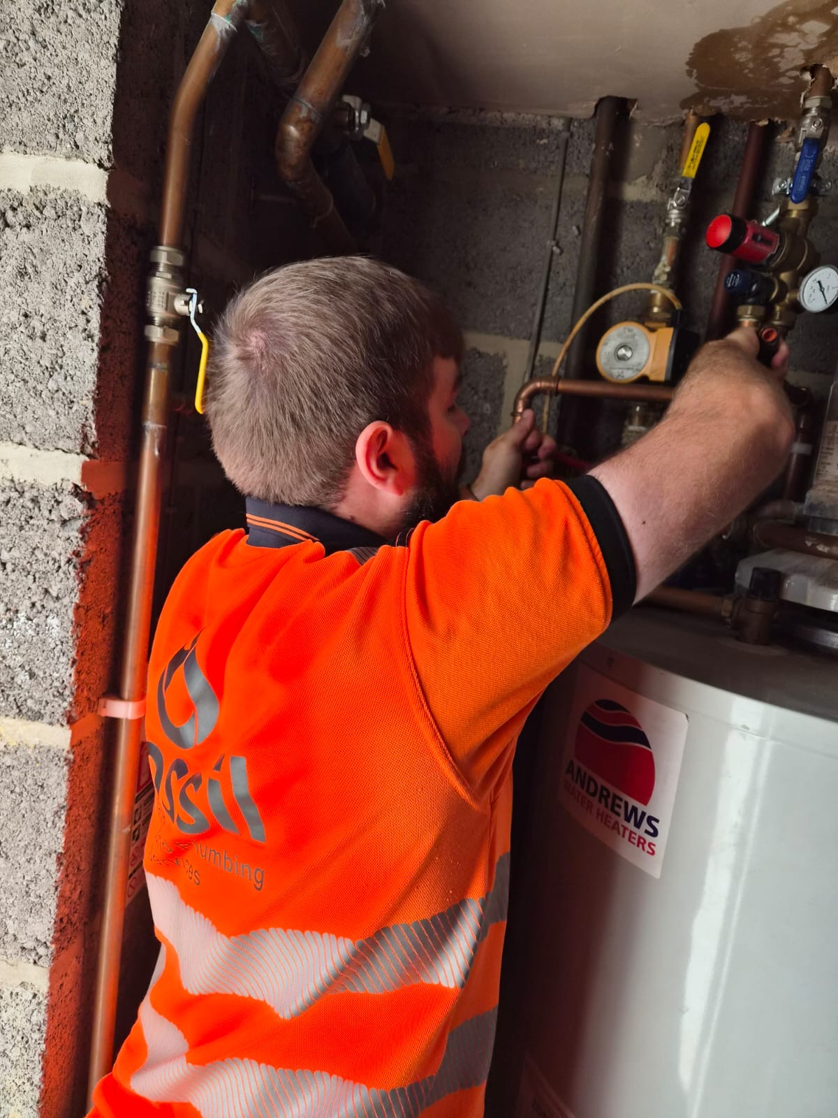 Fossil Heating engineer working on hot water cylinder pipework