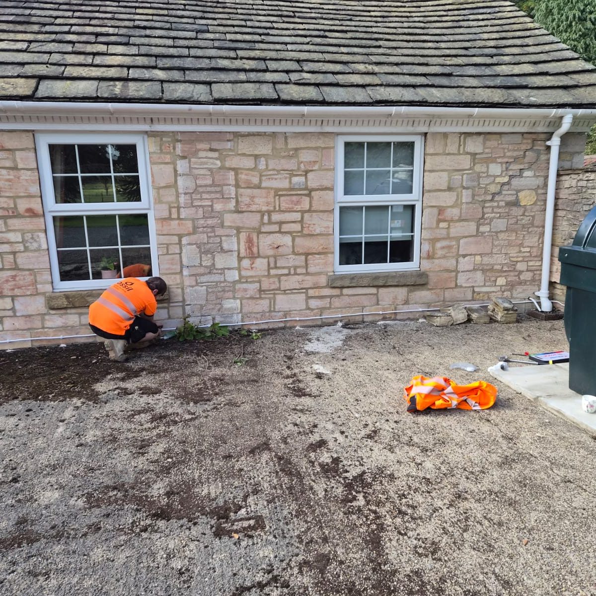 Fossil engineer installing external pipework on a stone cottage